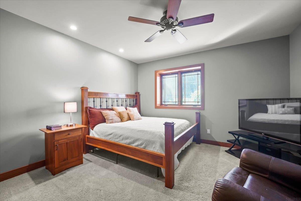 Bedroom with a wooden bed, ceiling fan, and window with blinds.