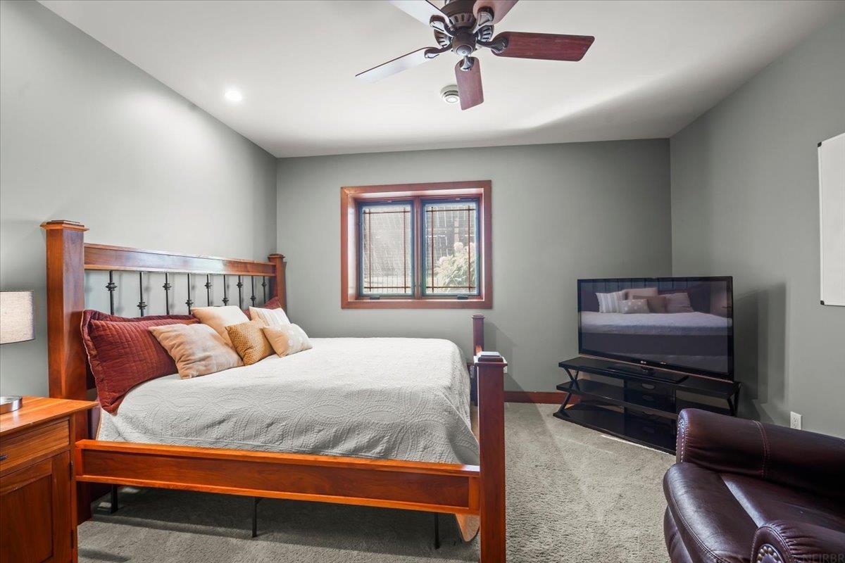 Bedroom with a wooden four-poster bed, gray walls, and a television beside the window.