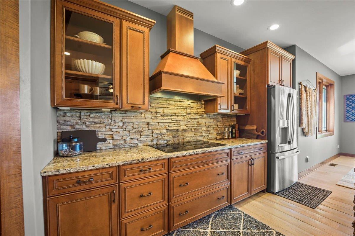 Kitchen with wood cabinetry, granite counters, and a stacked-stone backsplash.