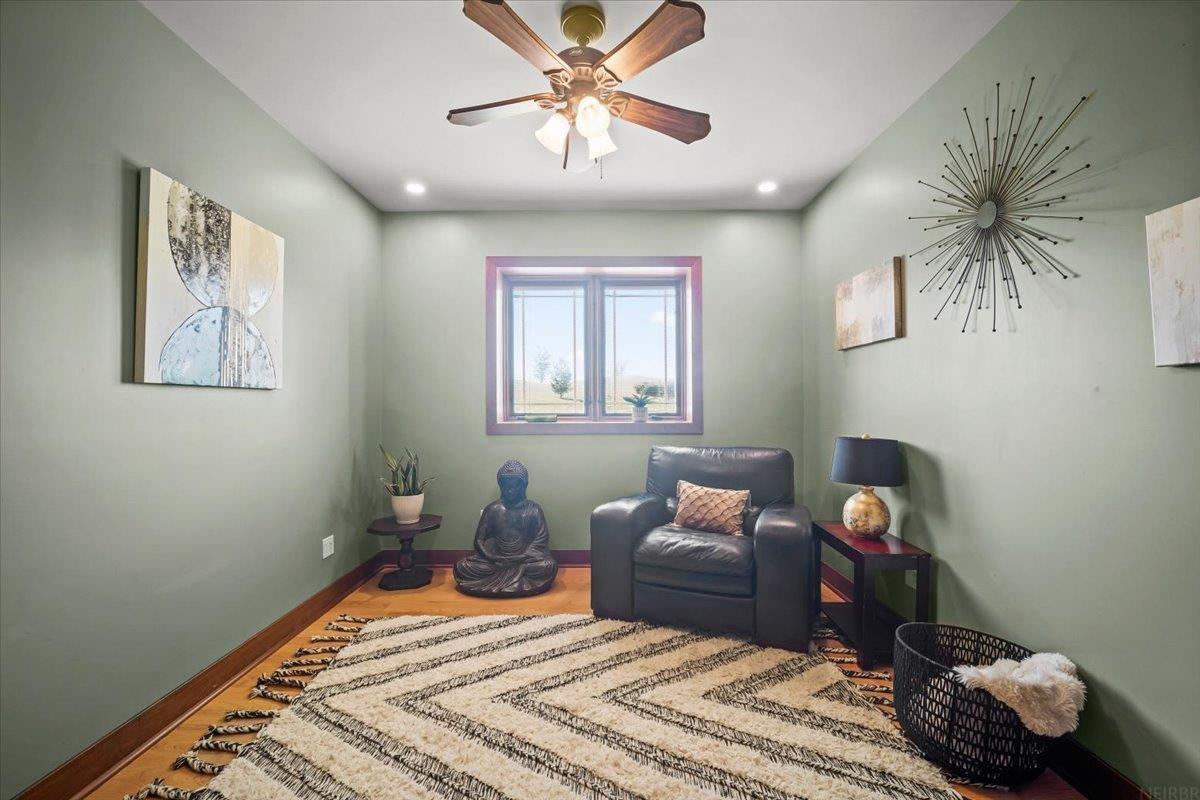 Furnished sitting room with a leather armchair, Buddha statue, and window overlooking open land.