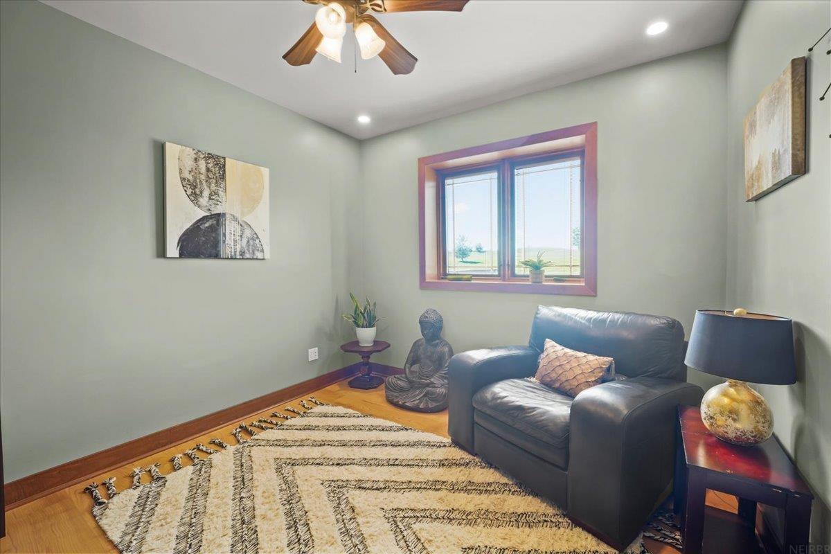 Furnished sitting room with a black leather chair, patterned rug, and window overlooking open fields.