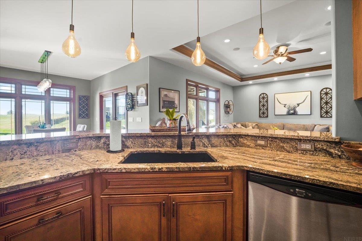 Kitchen with granite counters and dark wood cabinets, opening onto a living room with large windows.
