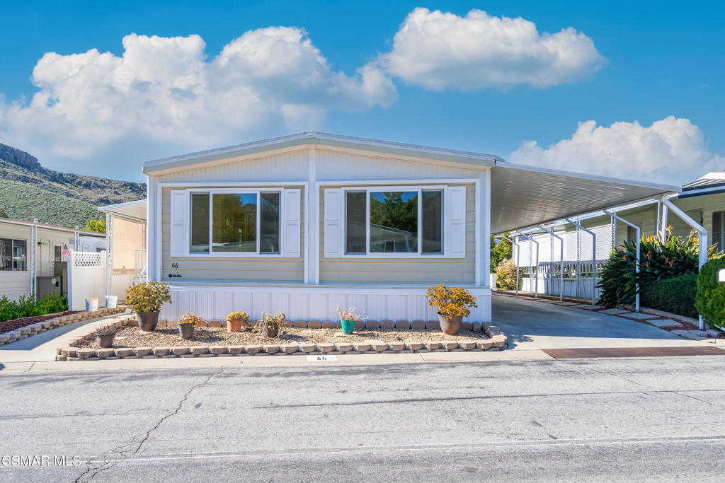 Single-story home with two large front windows, a covered carport, and a small rock-bordered garden.