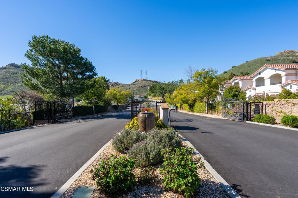 Gated neighborhood entrance with a landscaped median and hillside homes.