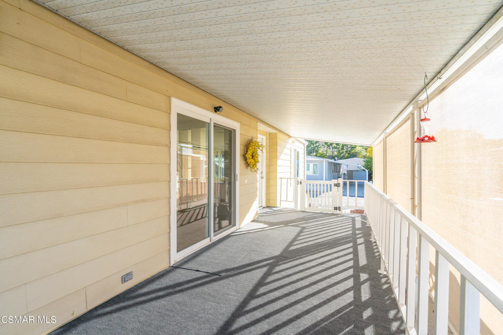 Covered patio with sliding glass doors, white railing, and a red hanging bird feeder.