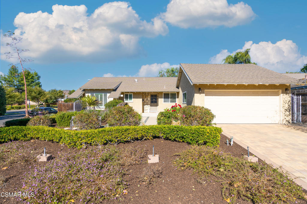Single-story beige home with a two-car garage and landscaped front garden.