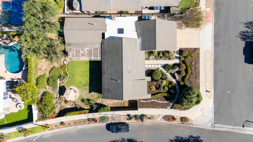 Aerial view of a home with a green lawn, landscaped garden paths, and a patio umbrella.