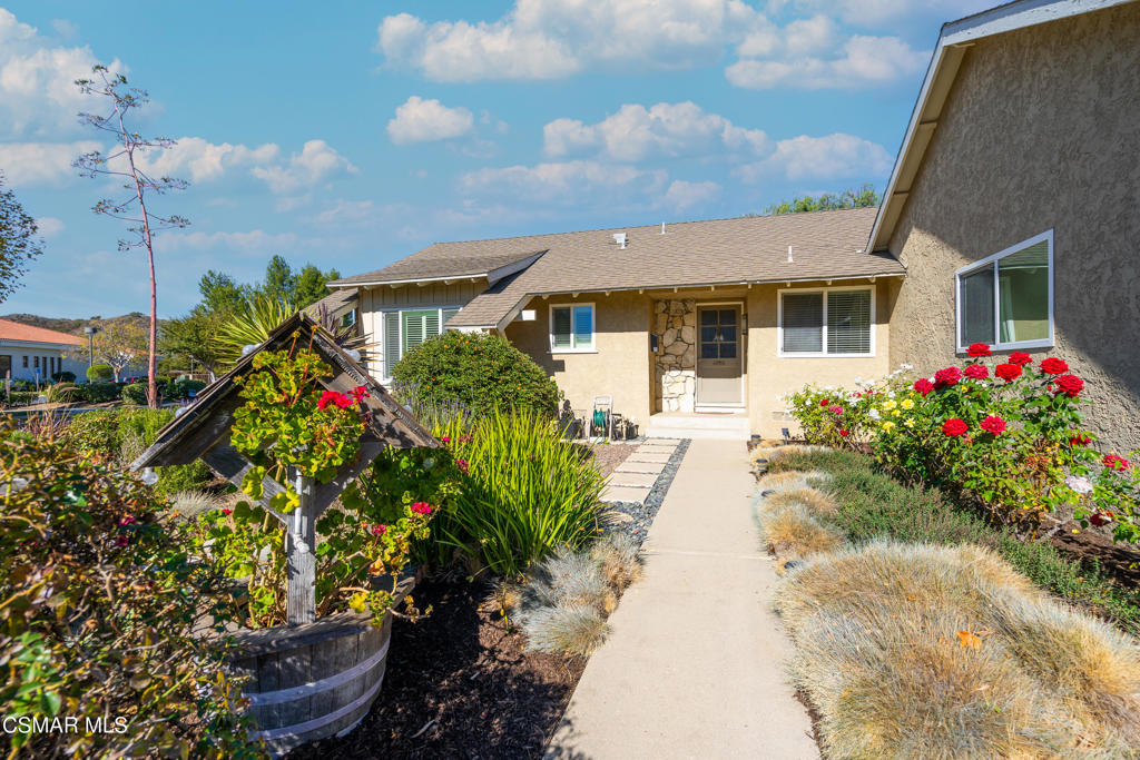 Beige stucco home with stone-accented entry and a flower-lined walkway.