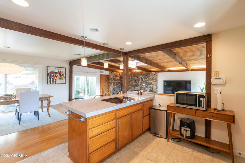 Open kitchen with a wood-cabinet island, exposed beams, and stone accent wall.