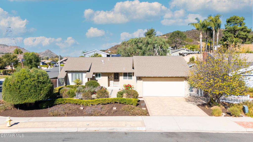 Single-story beige home with a two-car garage, landscaped front yard, and broad driveway.
