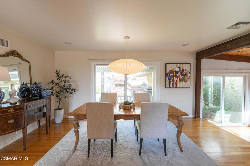 Dining room with a wooden table, upholstered chairs, pendant light, and sliding glass doors.