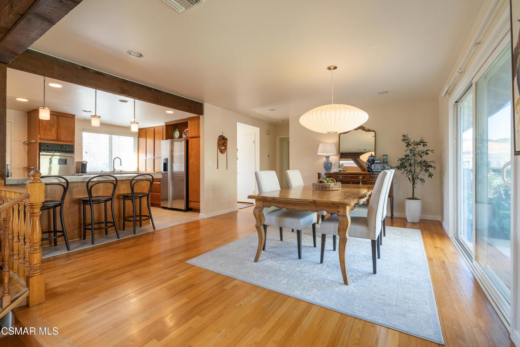 Dining room with a wooden table, pale rug, and sliding glass doors opening toward the kitchen.