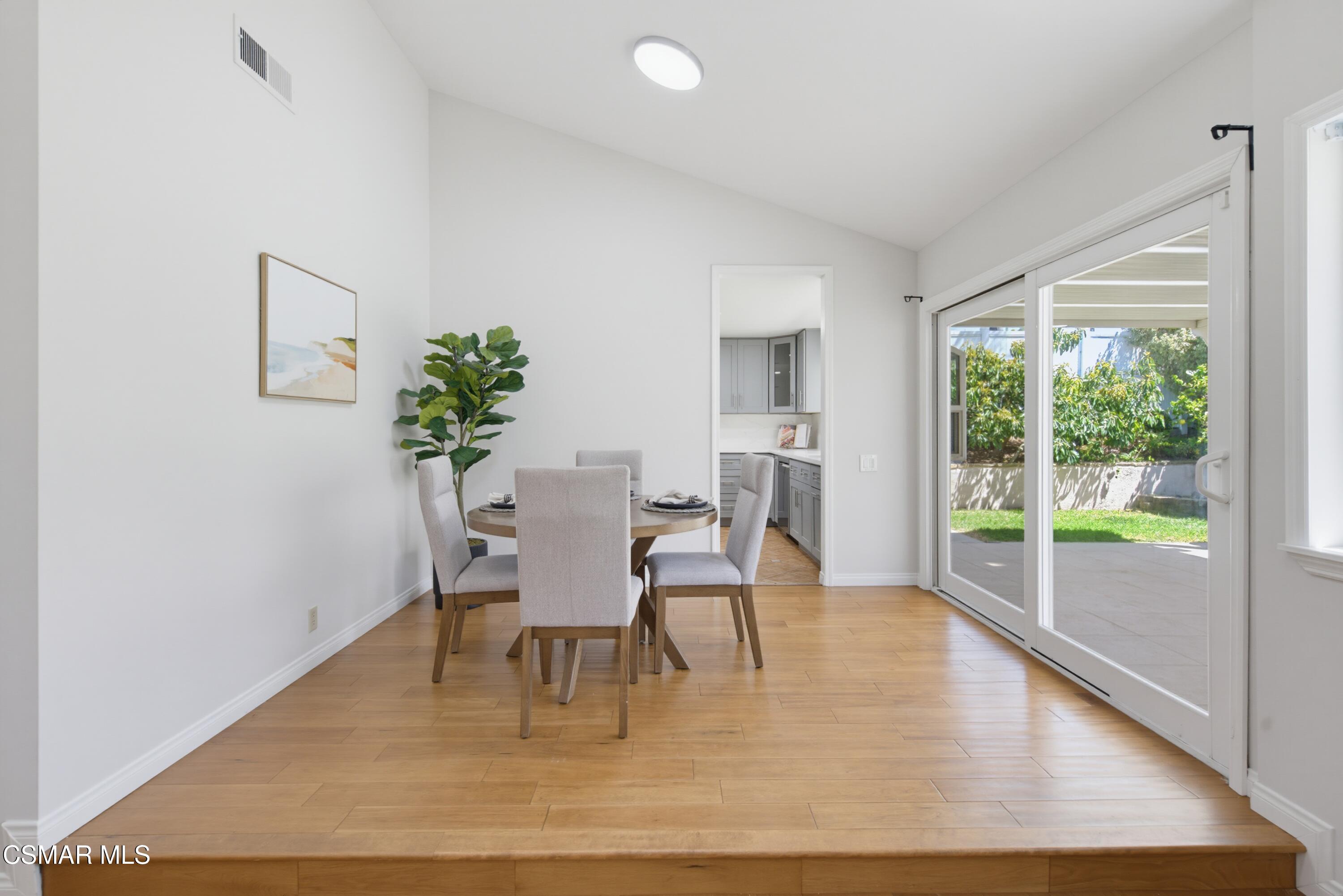 Dining room with a round table beside sliding glass doors opening to a covered patio and garden.