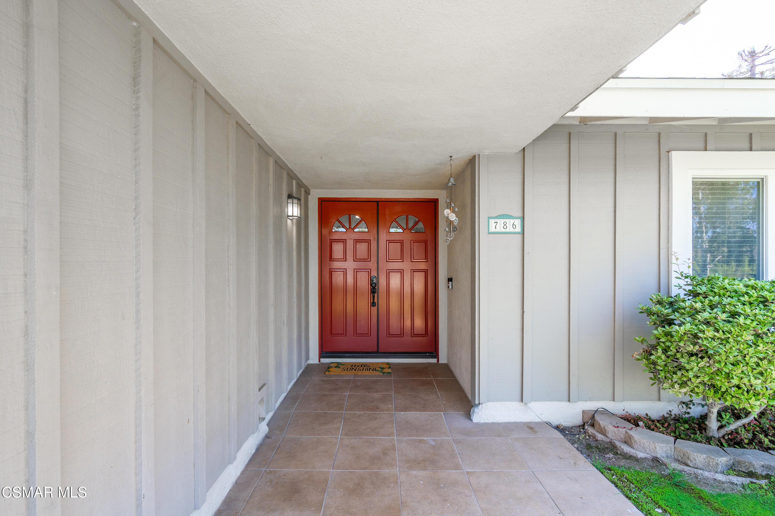 Covered house entry with a red double door, tiled porch, and 786 address plaque.