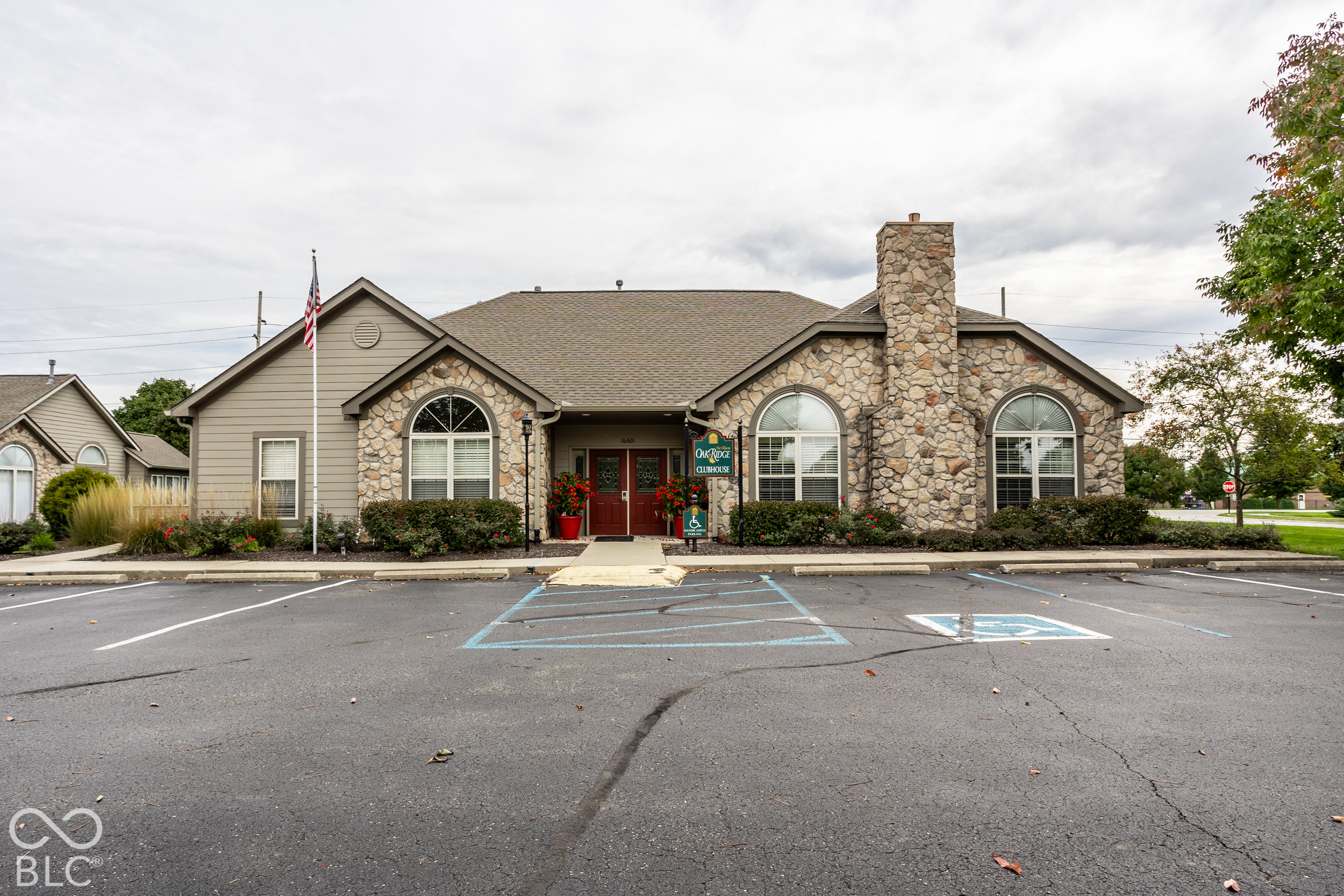 Oak Ridge Clubhouse exterior with stone facade, tall chimney, arched windows, and accessible parking.
