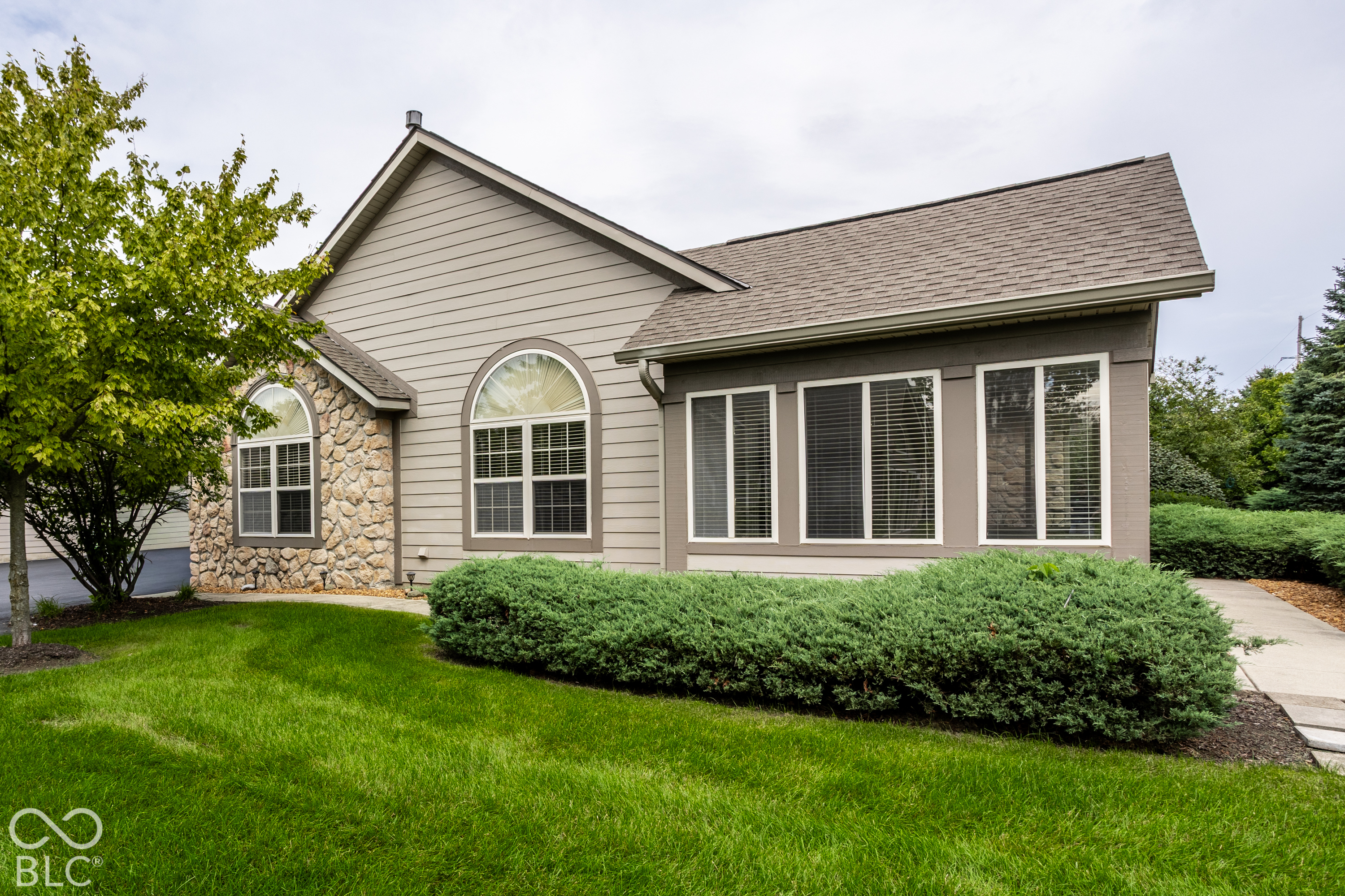 House exterior with stone facade, arched windows, and landscaped front lawn.
