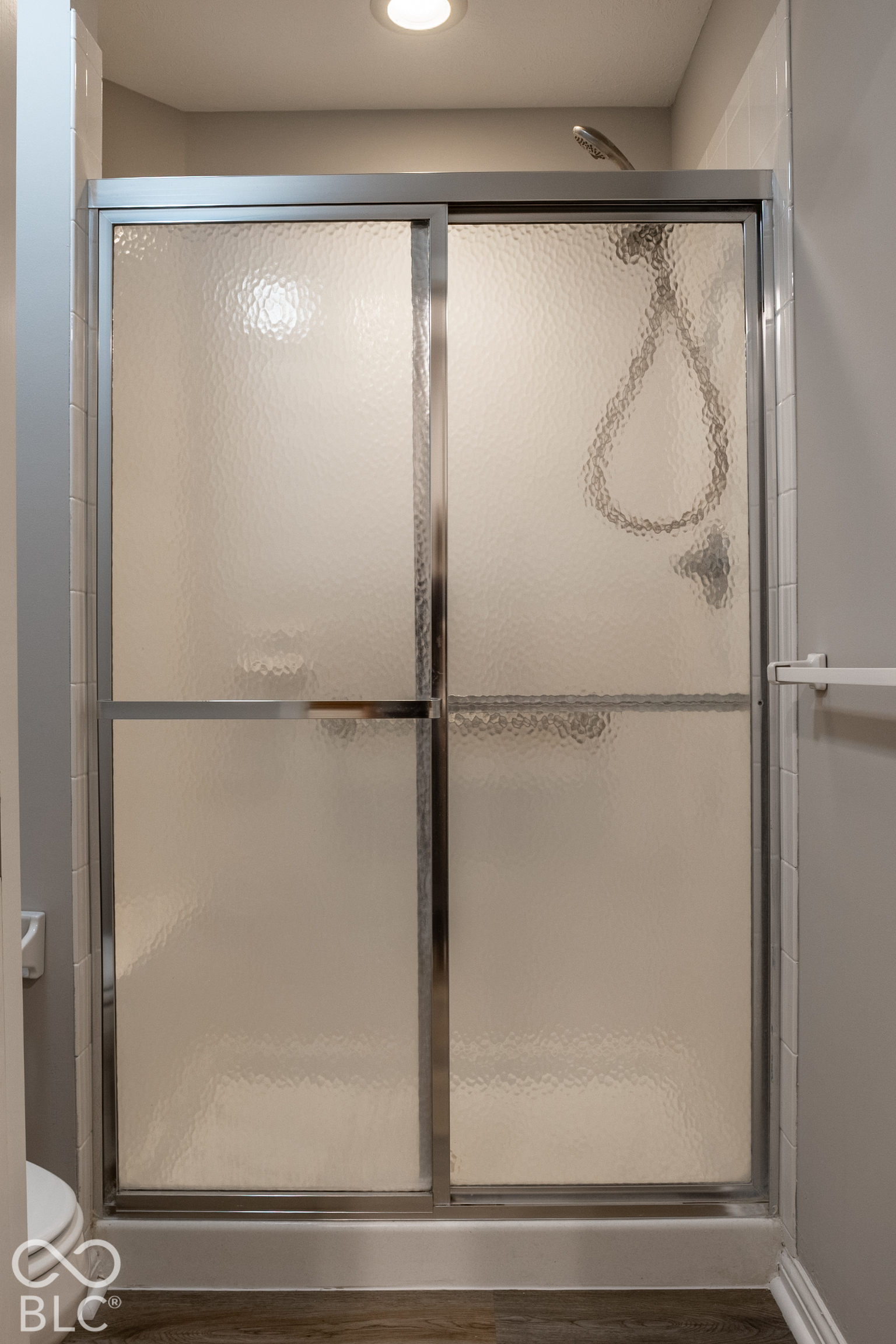 Bathroom shower with framed sliding doors of frosted, textured glass.
