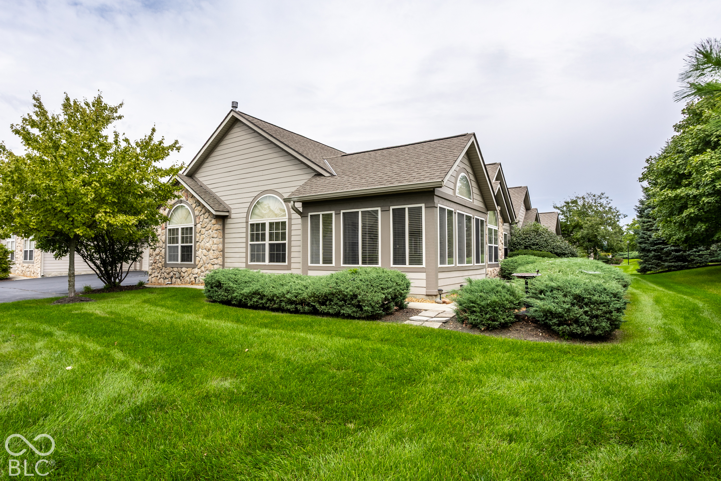 Home exterior with stone accents, arched windows, and a broad green lawn.