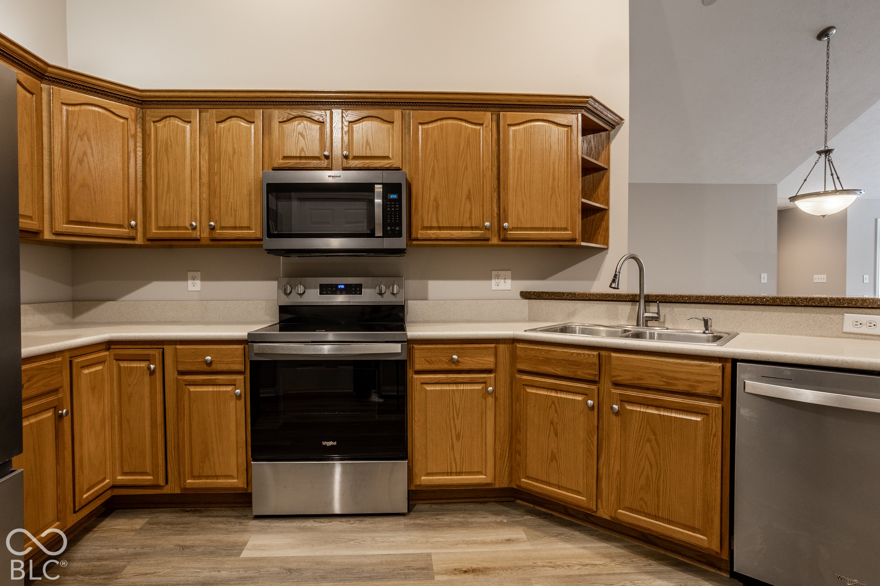 Kitchen with oak cabinetry, stainless steel appliances, and a double-basin sink.