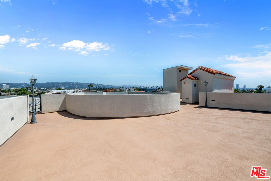 Rooftop terrace with curved parapet walls overlooking the city and distant hills.