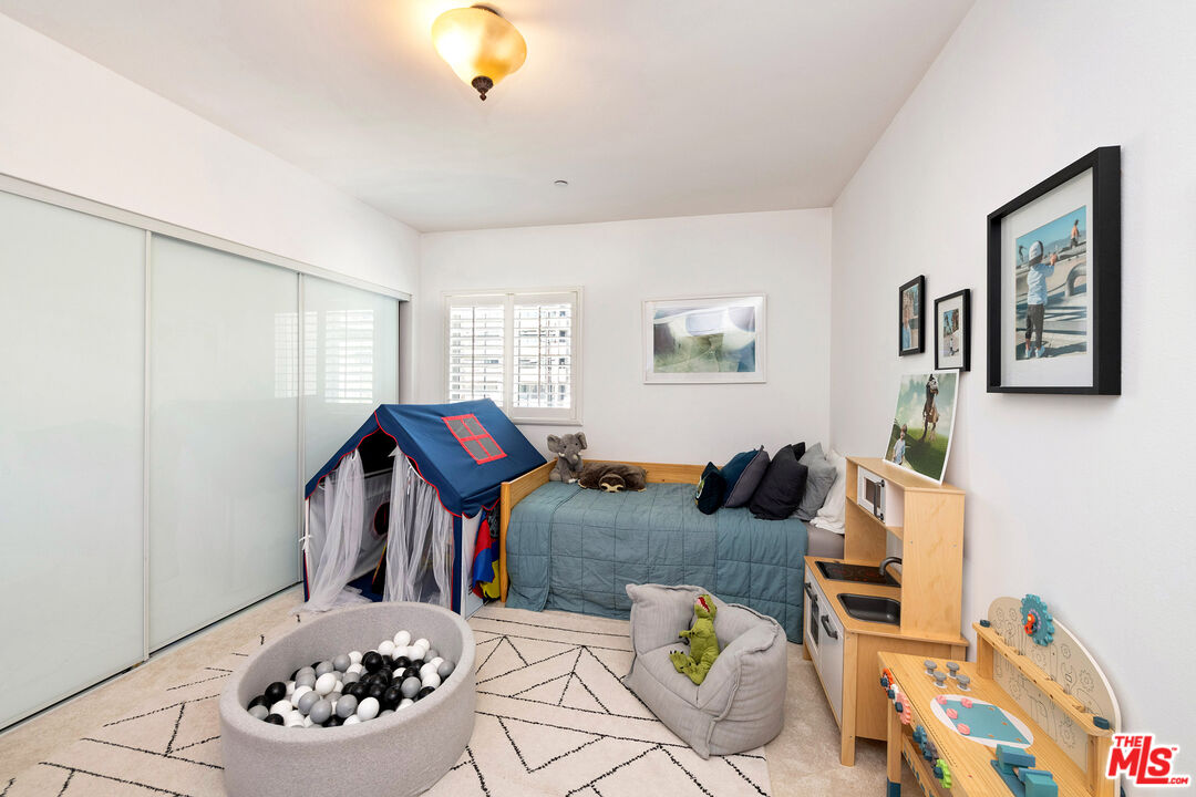 Child’s bedroom with a blue bed, play tent, ball pit and wooden toy kitchen.