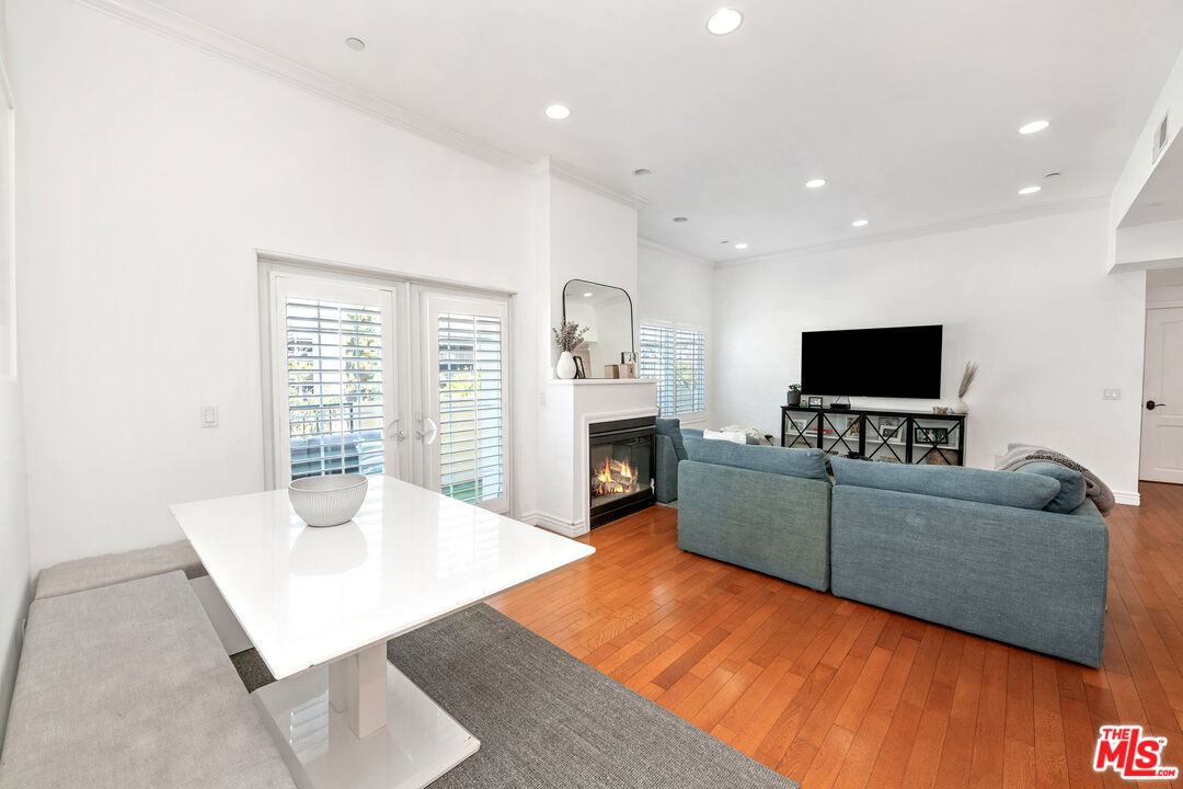 Open-plan living and dining room with a blue sectional, fireplace, and shuttered glass doors.