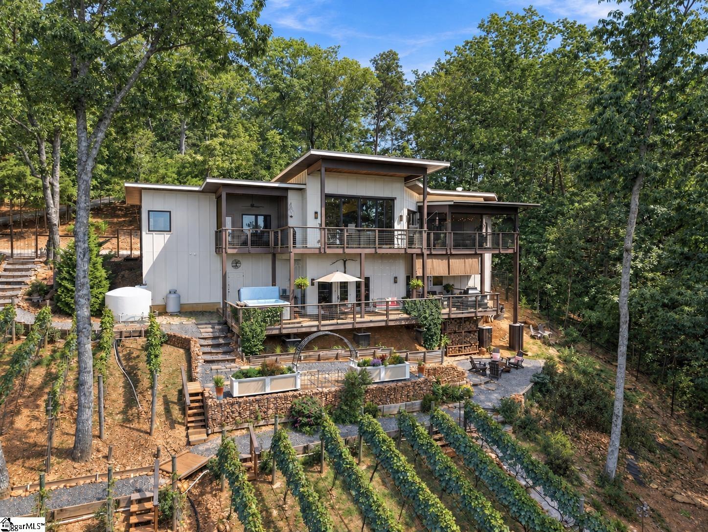 Modern hillside home with two levels of decks, landscaped terraces, and mature trees.