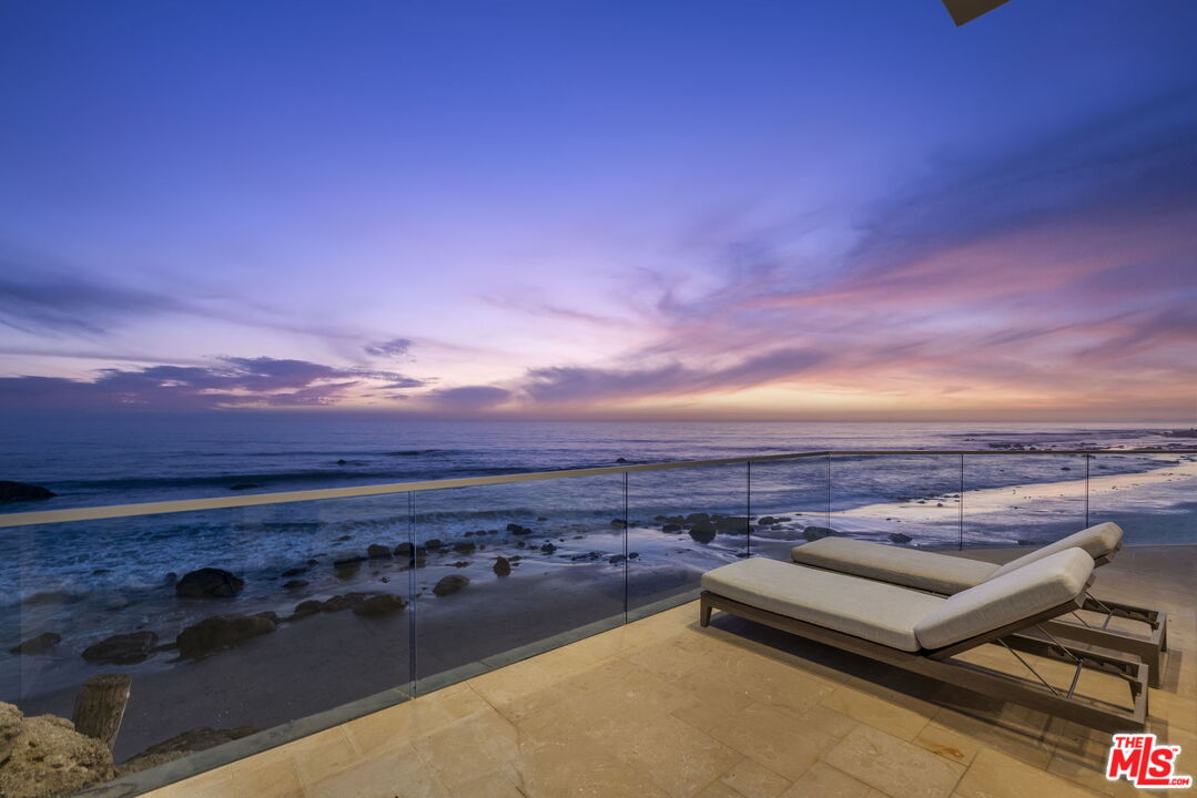Oceanfront terrace with two lounge chairs overlooking the beach at dusk.