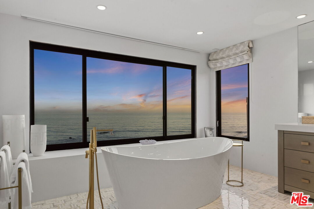 Bathroom with a freestanding tub and expansive sunset ocean views.