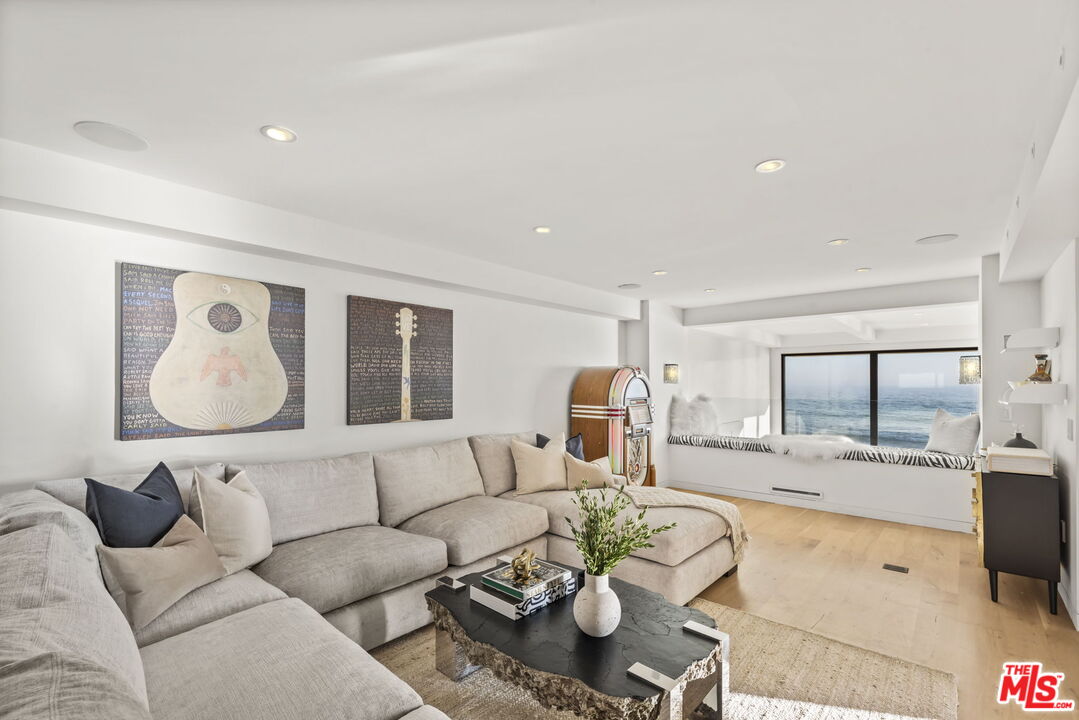 Furnished living room with a gray sectional, vintage jukebox, and ocean views through wide windows.
