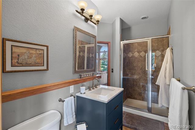 Bathroom with a blue vanity and a glass shower with brown tile.