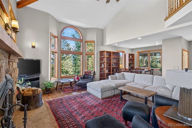 Living room with a stone fireplace, vaulted ceiling, arched windows, and a light-colored sectional.