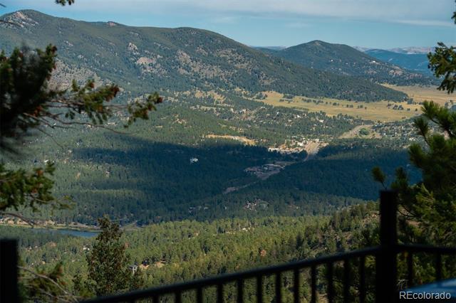 Mountain valley and forested hills viewed over a deck railing.