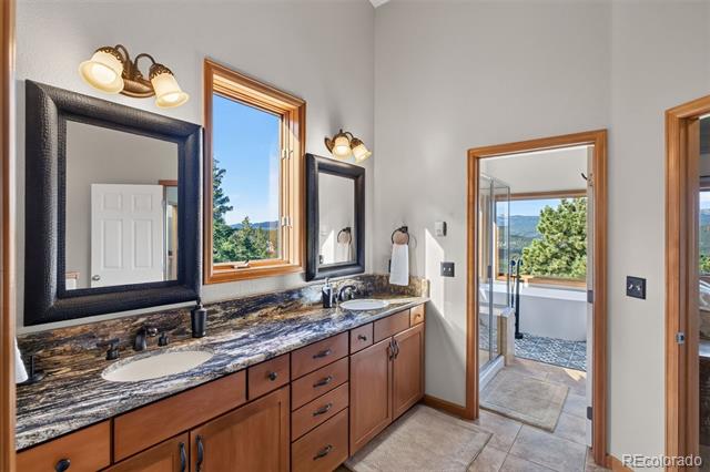 Bathroom with a long granite double vanity, wood cabinetry, and mountain views through the windows.