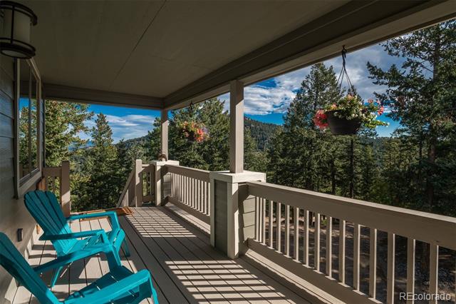 Covered deck with turquoise chairs overlooking wooded mountain scenery.