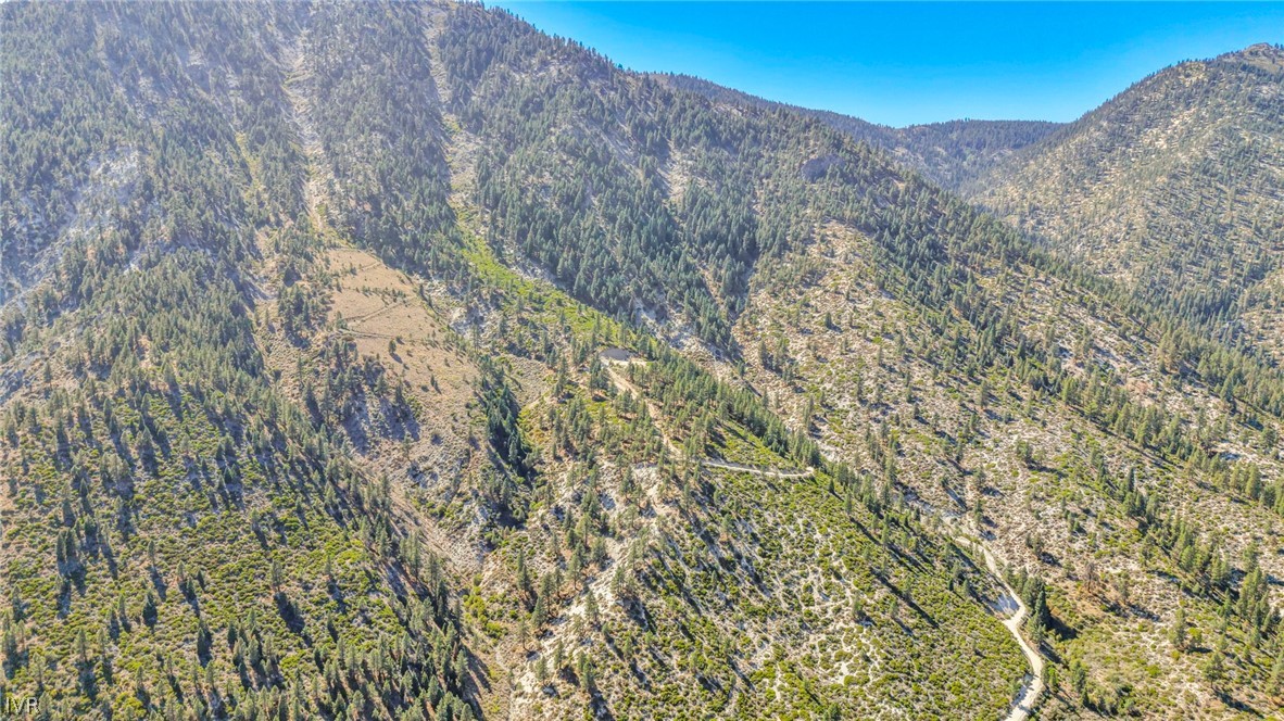 Aerial view of rugged, undeveloped mountain land with a winding dirt road.