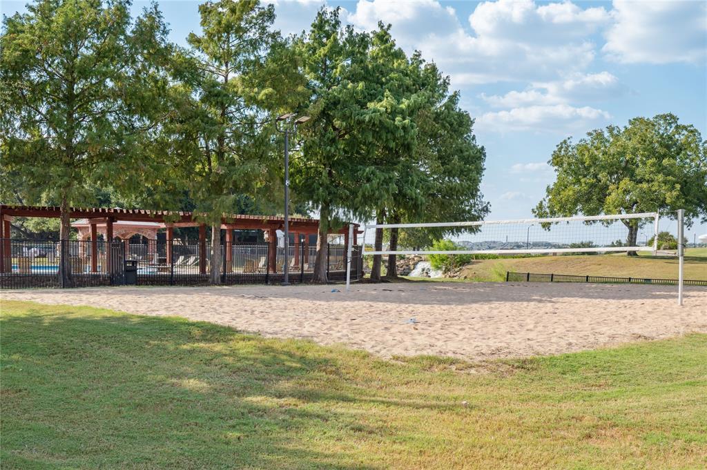 Sand volleyball court beside a shaded pavilion and swimming pool.