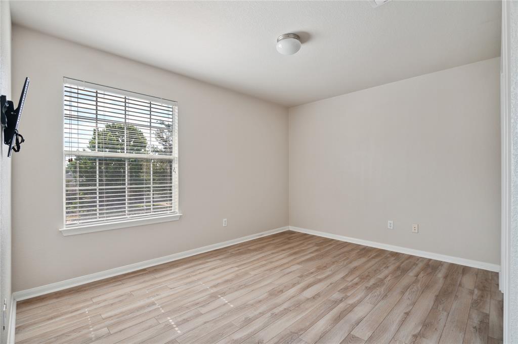 Empty room with wood-look flooring and a window with white blinds.