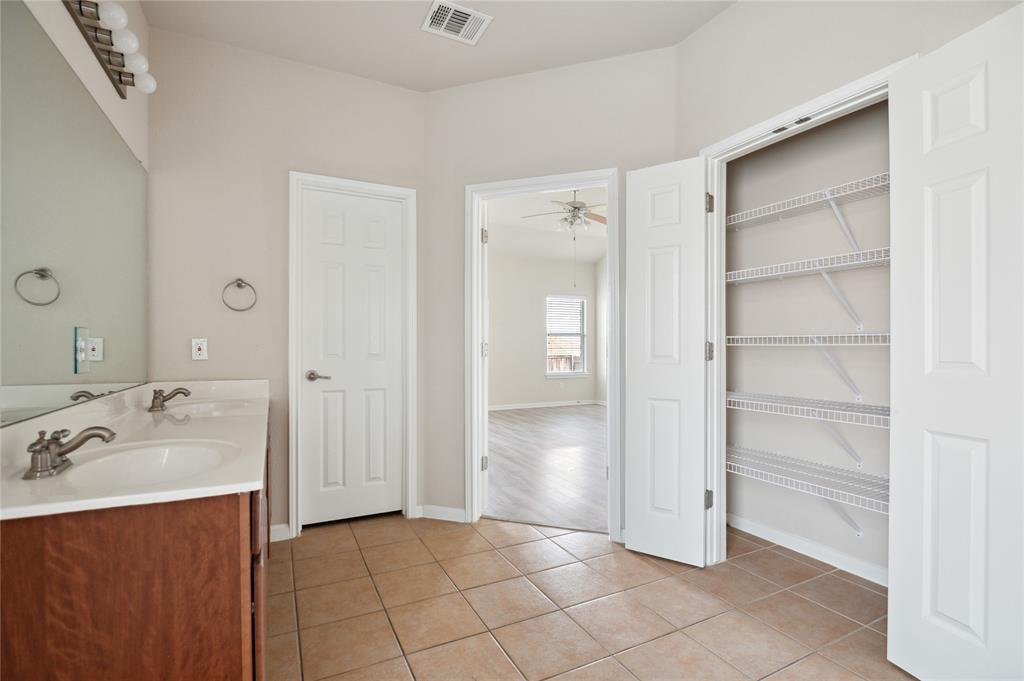 Bathroom with a double-sink vanity and open closet with white wire shelves.
