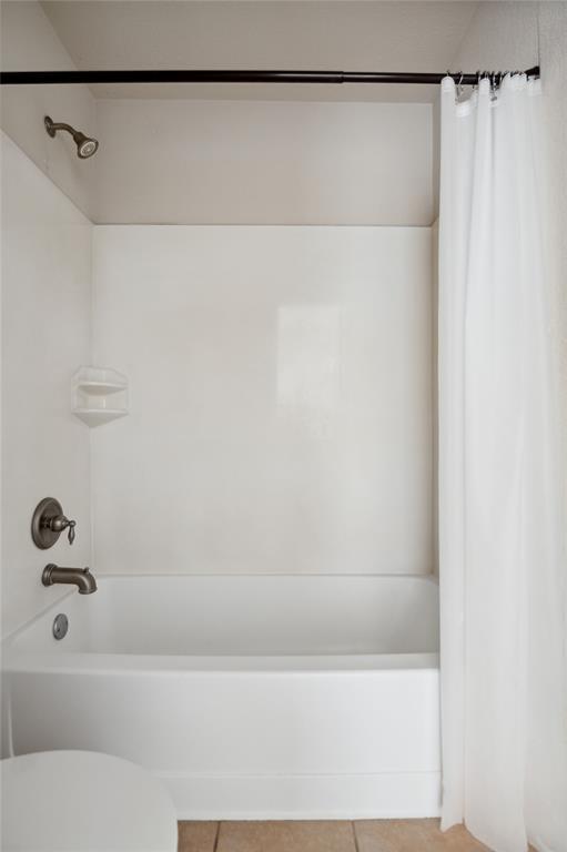 White bathtub and shower with a curtain, built-in soap shelf, and metal fixtures.
