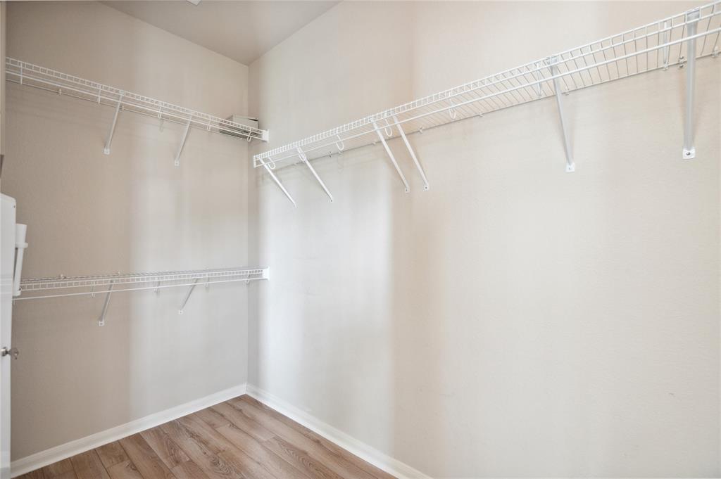 Walk-in closet with white wire shelving and wood-look plank flooring.