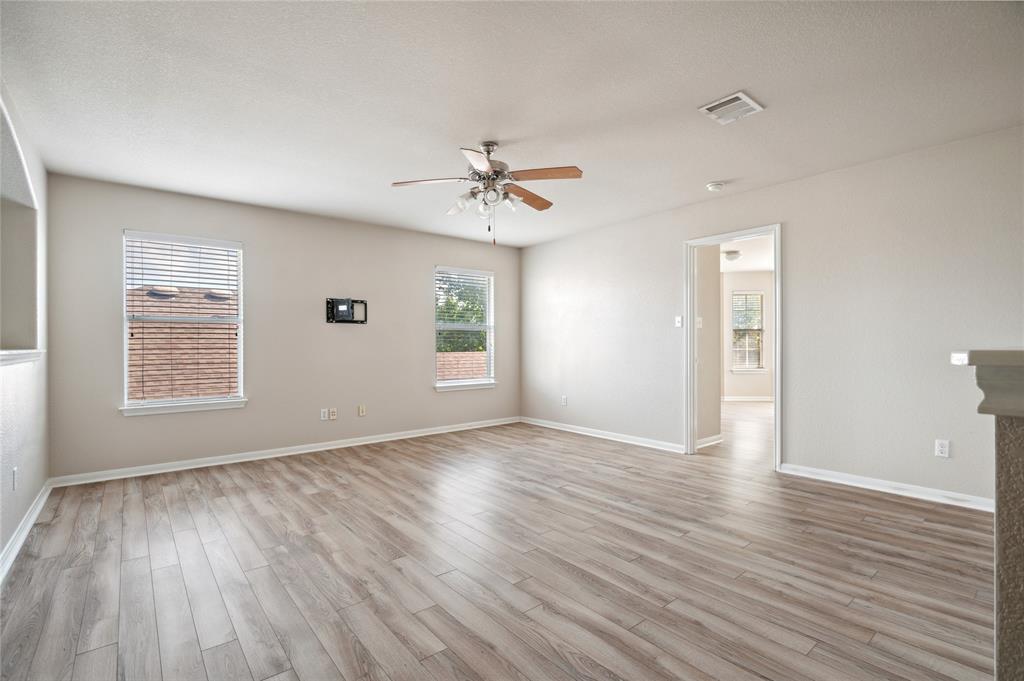 Empty living room with wood-look flooring, two windows, and a ceiling fan.