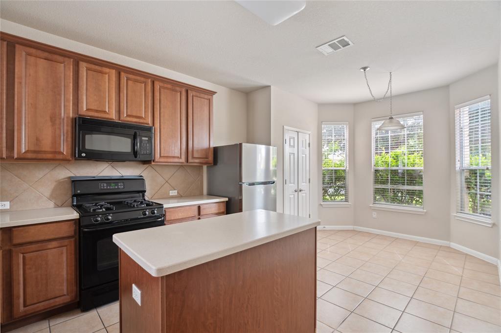 Kitchen with a large island, warm wood cabinets, and a bright windowed breakfast area.
