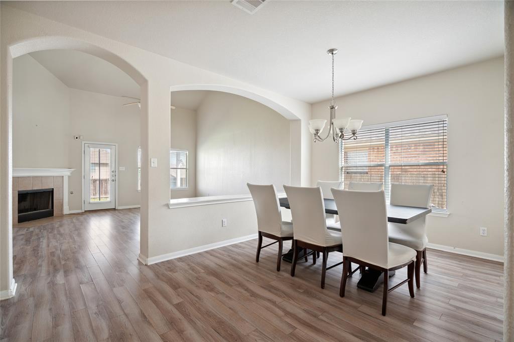 Dining room with upholstered chairs, a chandelier, arched openings, and a view of the adjacent fireplace.