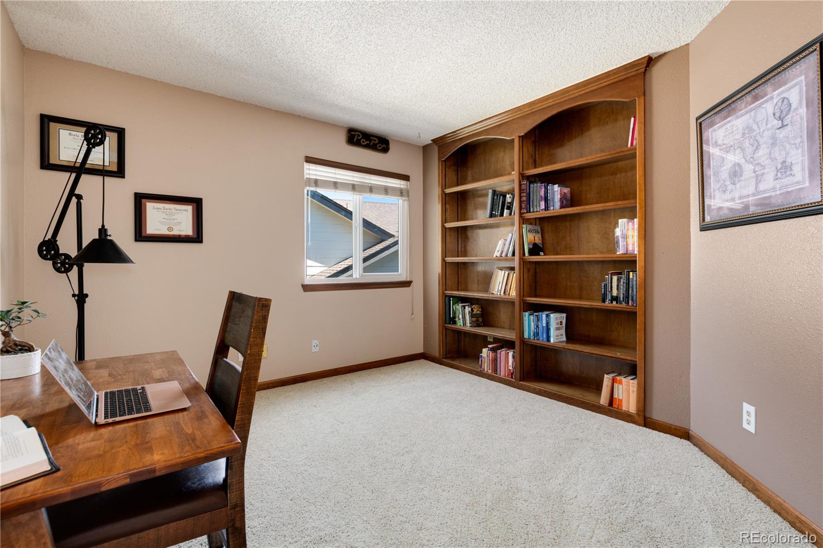 Home office with a built-in wooden bookcase and a desk with an open laptop.