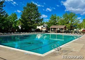 Outdoor swimming pool with a paved deck and covered pavilion.