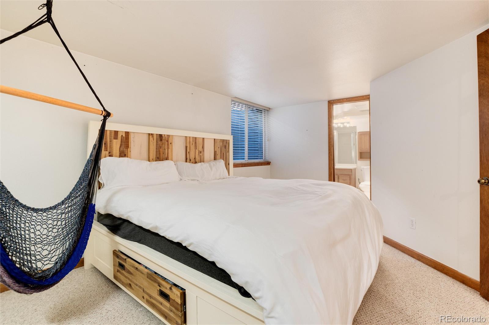 Bedroom with a white storage bed, wood headboard, and hanging hammock chair.