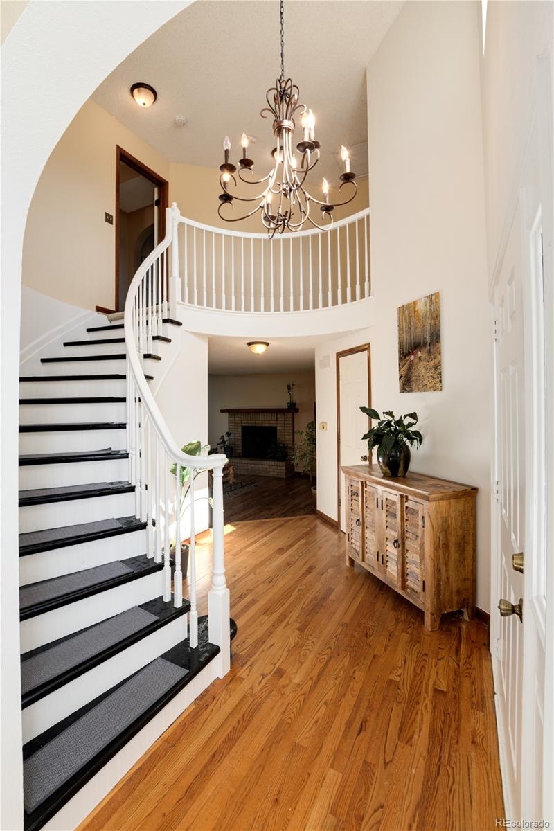 Entry foyer with a curved staircase, hardwood floors, and a chandelier.