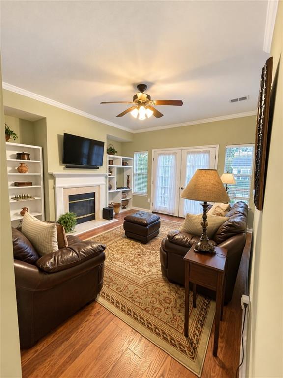 Furnished living room with leather seating, a fireplace, built-in shelves, and French doors.