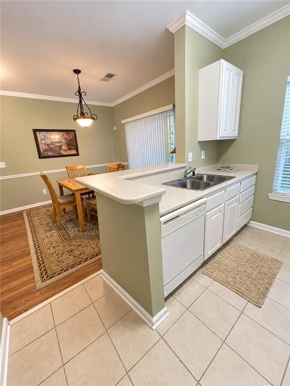 Kitchen with white cabinets and breakfast bar opening onto a dining area with a wooden table.